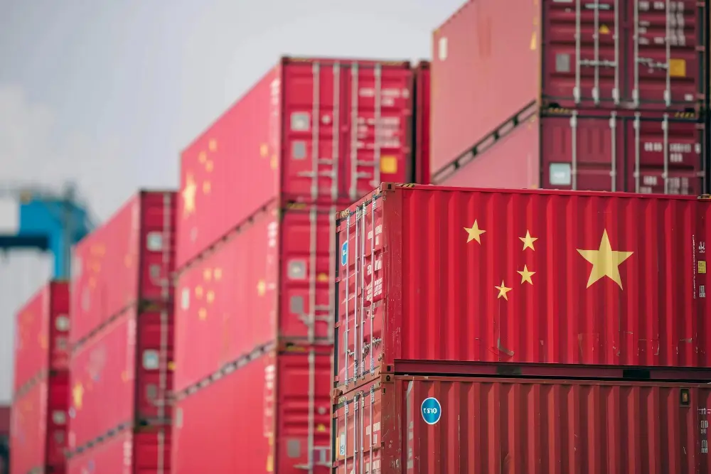 Contêineres vermelhos com bandeira da China empilhados em terminal portuário, ilustrando o processo de importação da China para o Brasil